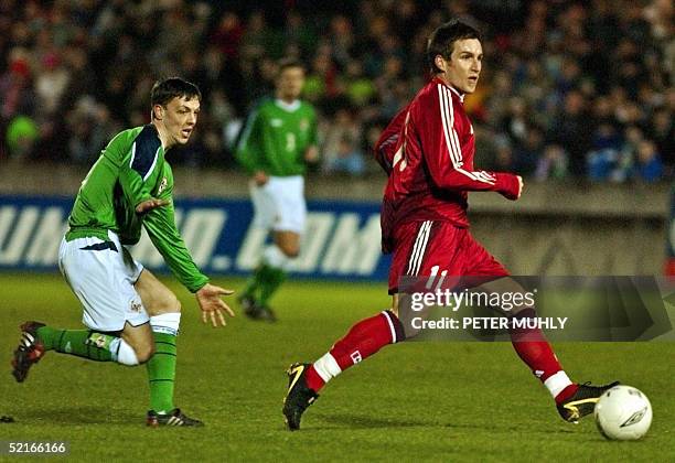 Northern Ireland football player Chris Baird tries to stop Canadian footballer Jim Brennan 09 February 2005 as he takes a shot towards the goal...