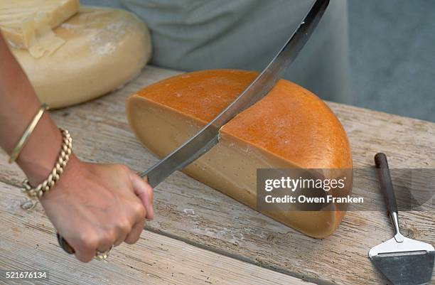 woman cutting cheese round - cheese production in netherlands stock pictures, royalty-free photos & images