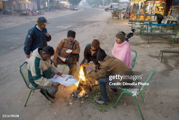 people warming up fire at bus stop, jodhpur, rajasthan, india - bus wrap stockfoto's en -beelden