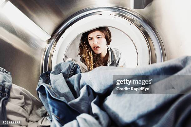 pretty woman pulling face at laundry in drier - onaangename geur stockfoto's en -beelden