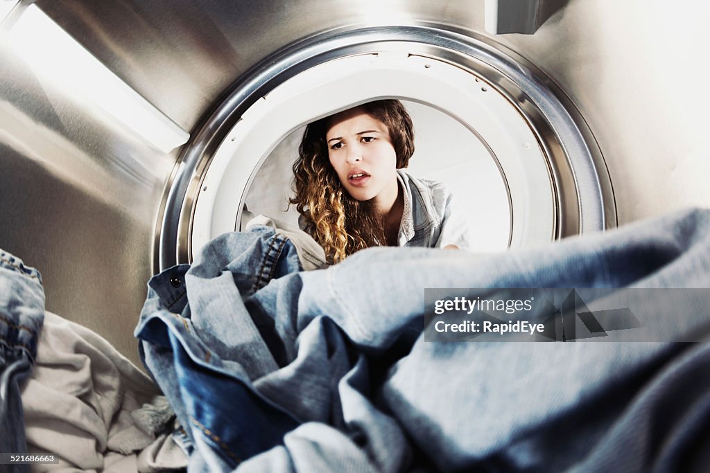 Pretty woman pulling face at laundry in drier