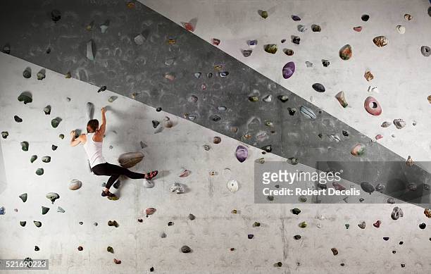female climber clinging to climbing wall - herausforderung stock-fotos und bilder