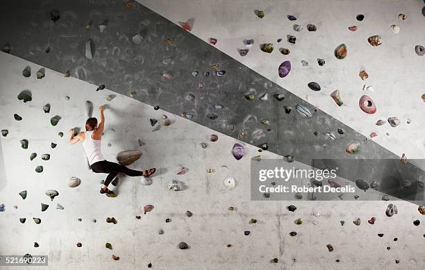 female climber clinging to climbing wall - klimmuur stockfoto's en -beelden