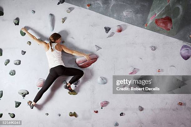 female climber scaling climbing wall - venciendo la adversidad fotografías e imágenes de stock