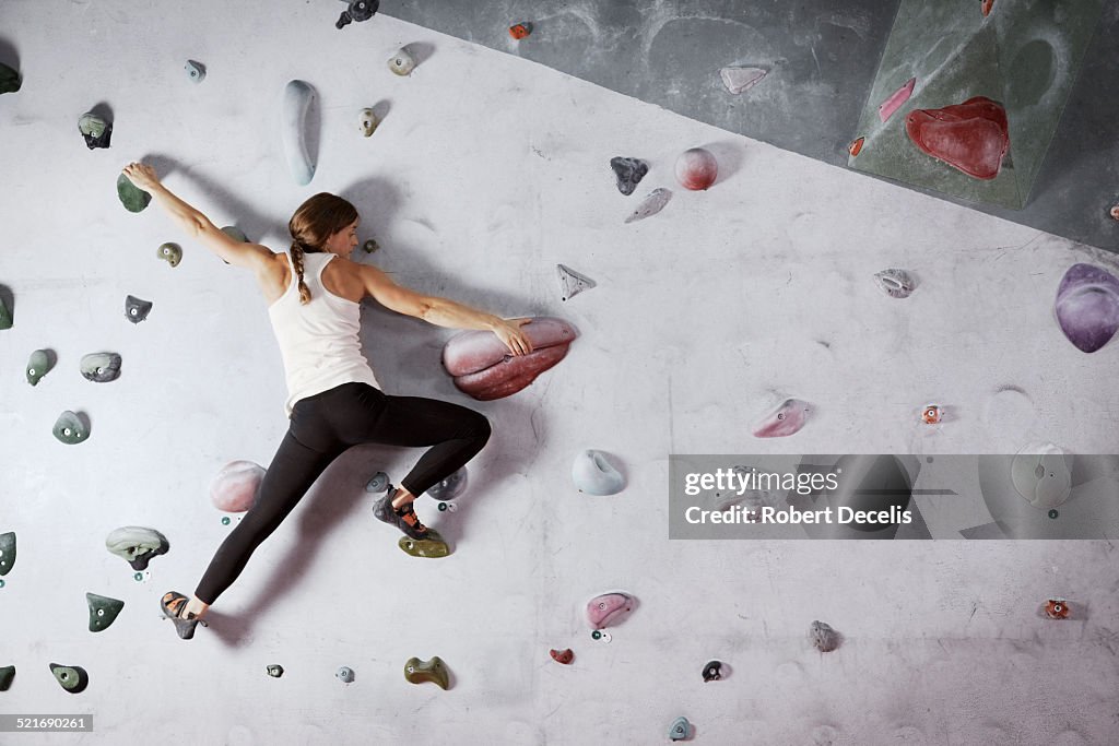 Female climber scaling climbing wall