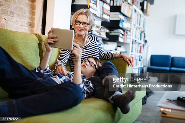 mature mother and son browsing the internet - surprised woman looking at tablet stock pictures, royalty-free photos & images