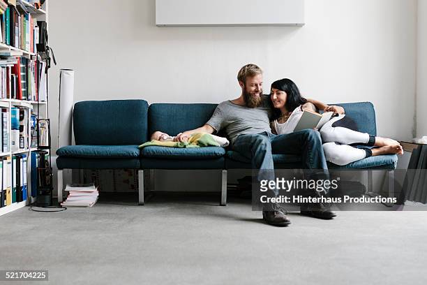 young couple relaxing with their new born baby - sofa stock pictures, royalty-free photos & images