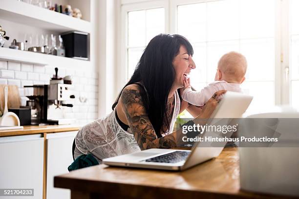 young tattoed mother with newborn baby - parent computer stock pictures, royalty-free photos & images