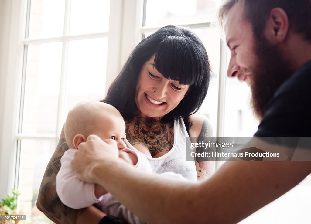 Young Family With Newborn Baby Beside Window