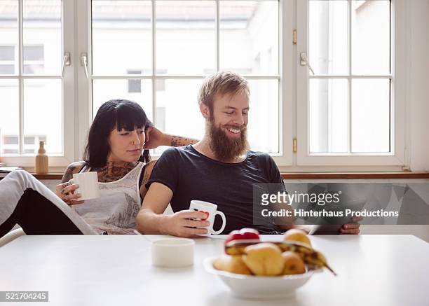 young couple with digital tablet - hipster in a kitchen stock-fotos und bilder