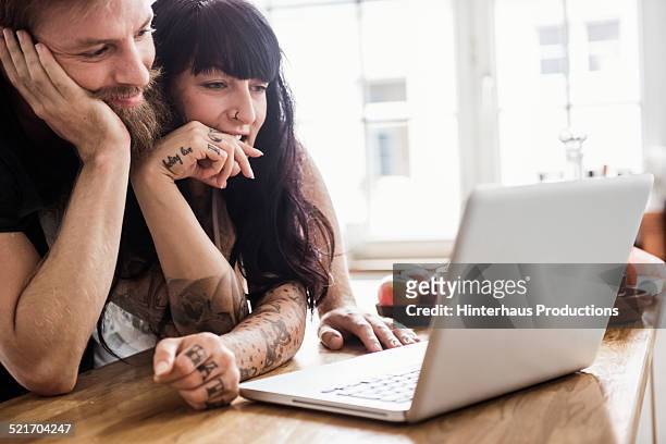 young couple with laptop - neugierde stock-fotos und bilder