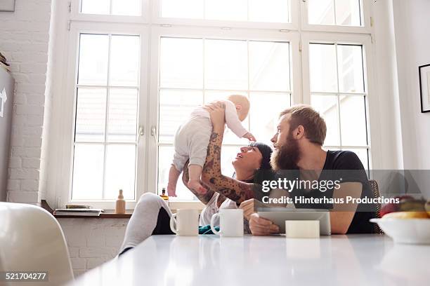 young family with newborn baby - couple in kitchen foto e immagini stock