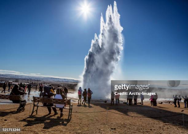 tourist watching strokkur geyser erupting, iceland - strokkur stock pictures, royalty-free photos & images