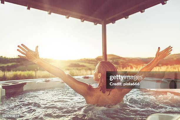 femme avec bras ouverts dans le bain à remous jacuzzi - bain à remous photos et images de collection