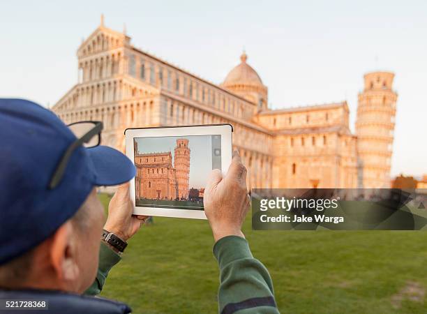 tourist with ipad photographing the leaning tower of pisa, sunset - apple inc stock pictures, royalty-free photos & images