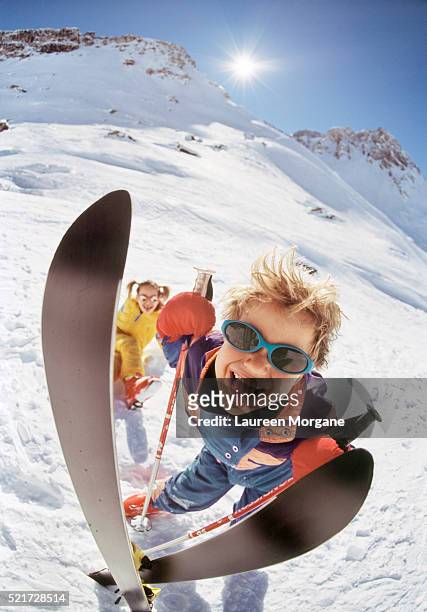 boy with skis sticking out his tongue, girl in the background - tignes stock pictures, royalty-free photos & images