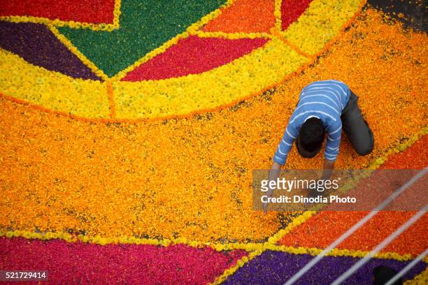 residents making colourful flower rangoli on road for immersion celebration of lord ganesh, sangli, maharashtra, india - rangoli stock-fotos und bilder