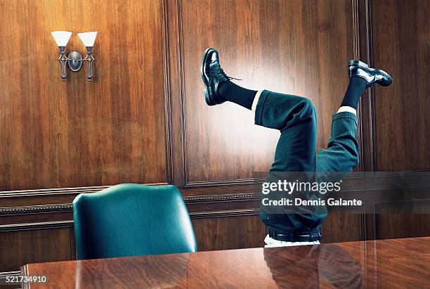 businessman standing on head in boardroom - archive the office stockfoto's en -beelden
