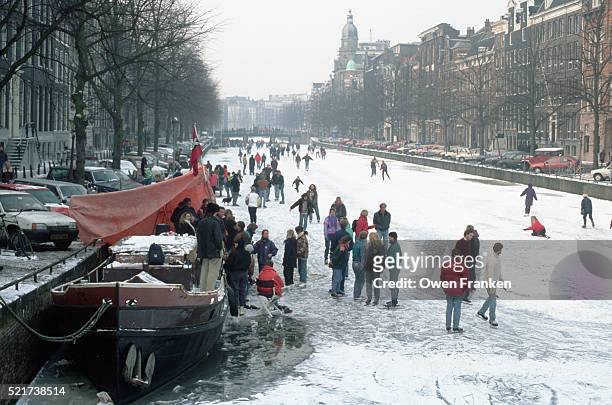 ice skaters on frozen canal in amsterdam - amsterdam winter stock pictures, royalty-free photos & images