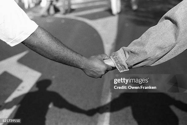 black and white demonstrators hold hands - racism stock pictures, royalty-free photos & images