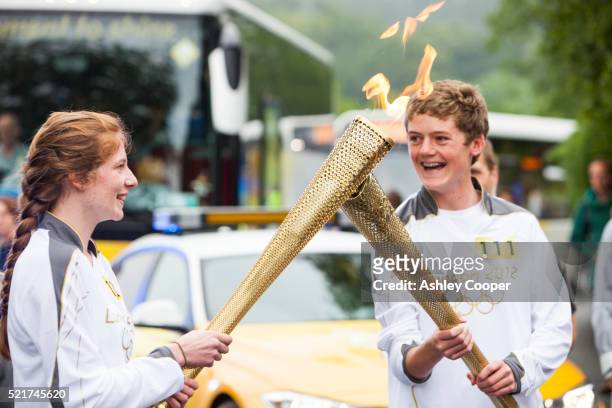 a change over of olympic torch bearers in ambleside, lake district, uk. - torch bearer stock pictures, royalty-free photos & images