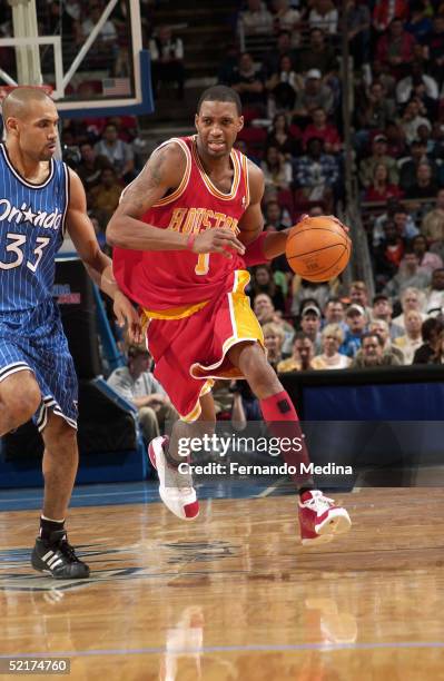 Tracy McGrady of the Houston Rockets moves the ball against Grant Hill of the Orlando Magic during the game at TD Waterhouse Centre on January 20,...