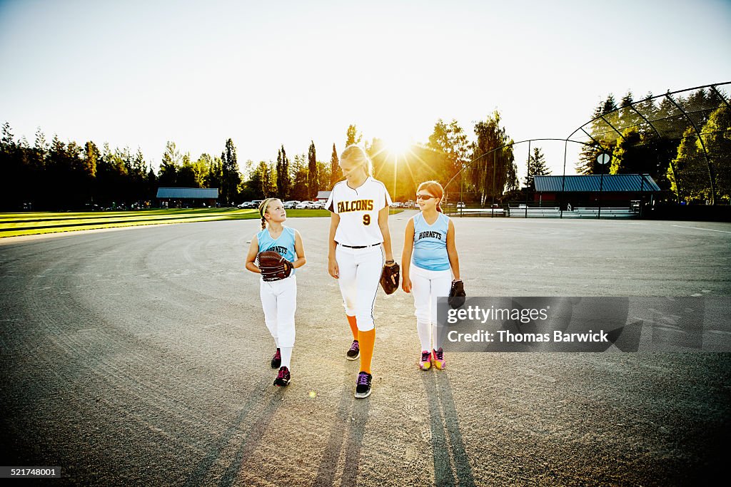 Adult softball player walking with young players