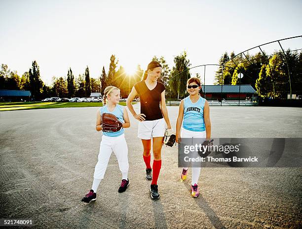 Softball coach walking with two young players