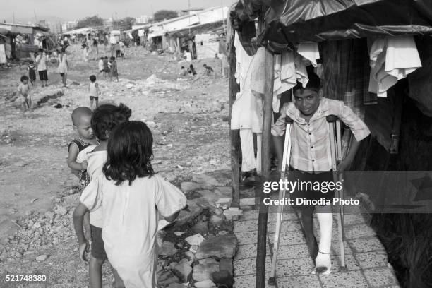 boy with leg in plaster on crutches, malvani slum, malad, bombay mumbai, maharashtra, india - indian crutch stockfoto's en -beelden