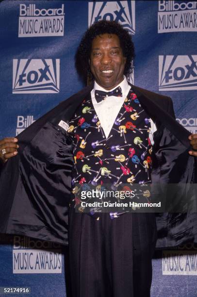 American blues guitarist Buddy Guy, backstage at the 4th Annual Billboard Music Awards, opens his tuxedo jacket to display a colorful vest covered in...