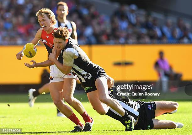 Jayden Hunt of the Demons handballs whilst being tackled by Taylor Adams and Nathan Brown of the Magpies during the round four AFL match between the...
