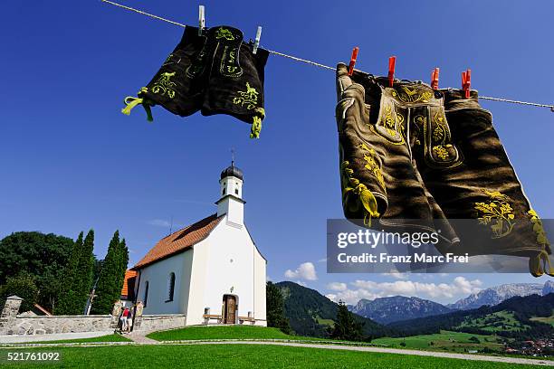 traditional lederhosen in front of st. peter chapel in buching, allgau, bavaria - allgau stock pictures, royalty-free photos & images