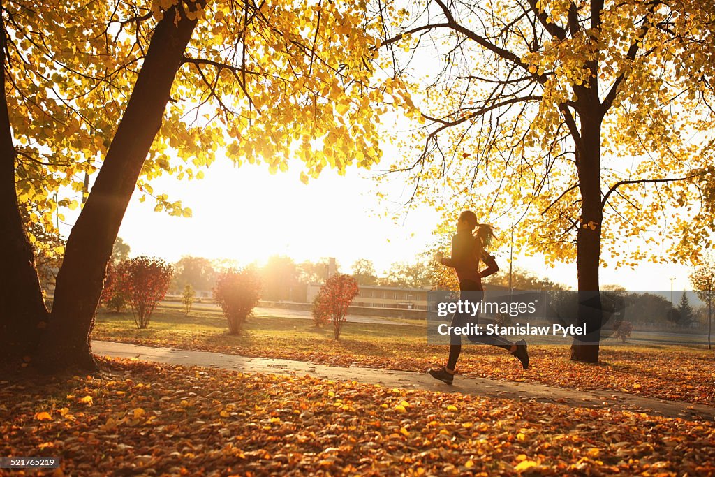 Young woman running in park, autumn