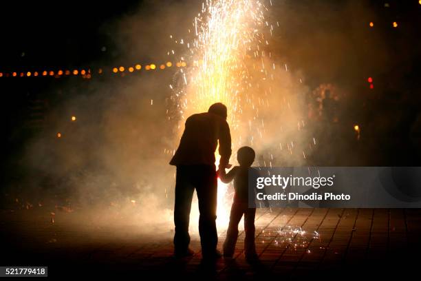 father and son bursting fire crackers while celebrating diwali deepawali, festive-of-lights at marine-drive in bombay - fire works stock pictures, royalty-free photos & images