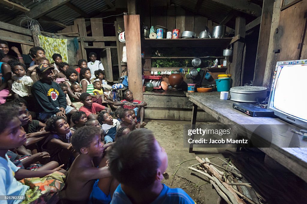 Indigenous Agta watch television together with electricity powered by a generator