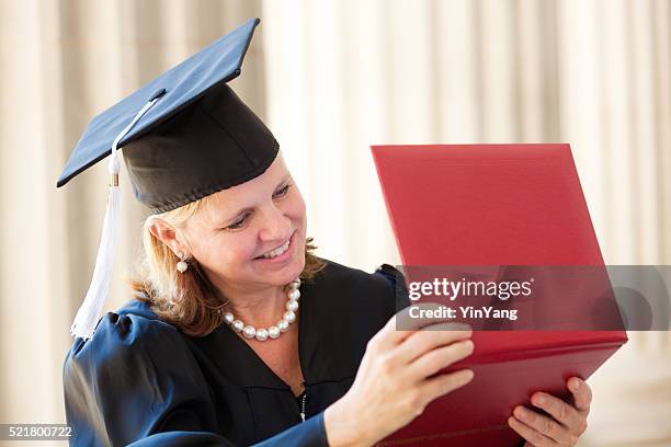 feliz media edad mujer mirando a diploma de graduación horizontal - masters degree fotografías e imágenes de stock