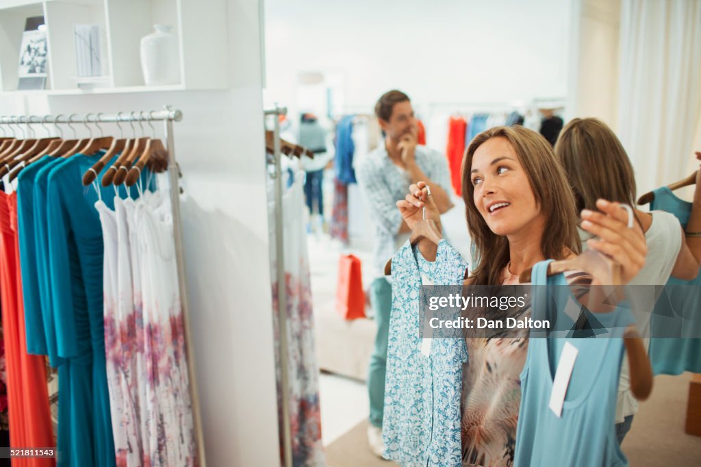 Man helping girlfriend pick dresses in clothing store