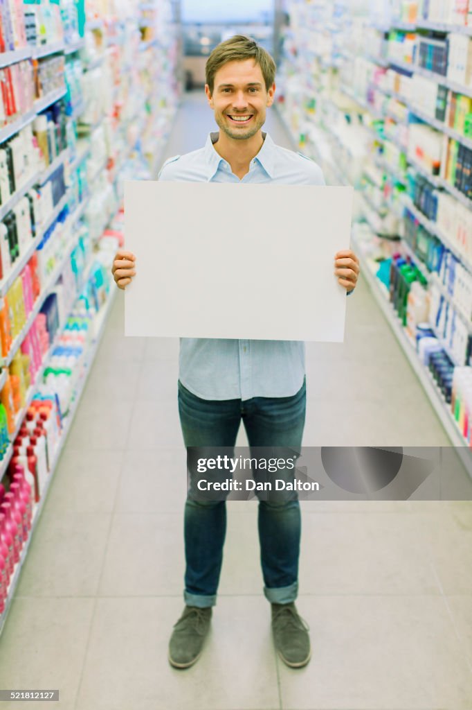 Man holding blank card in grocery store aisle