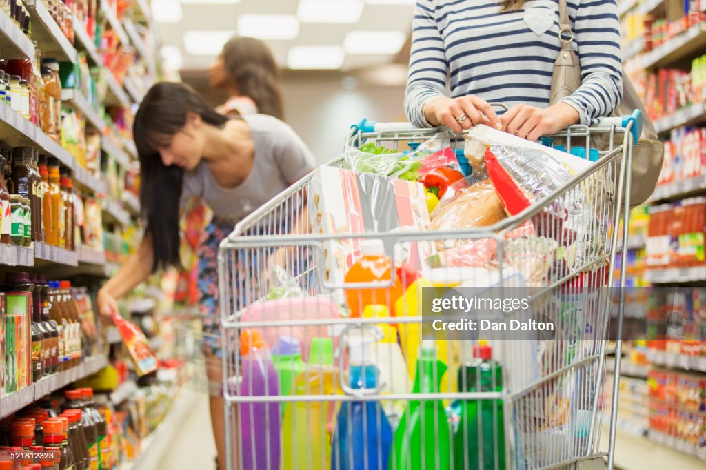 Frau schiebt vollen Einkaufswagen im Lebensmittelgeschäft