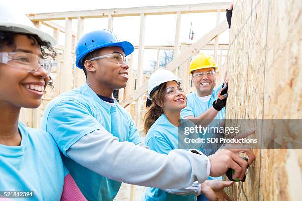 diverse team of volunteers build wall in charity home - community development stock pictures, royalty-free photos & images