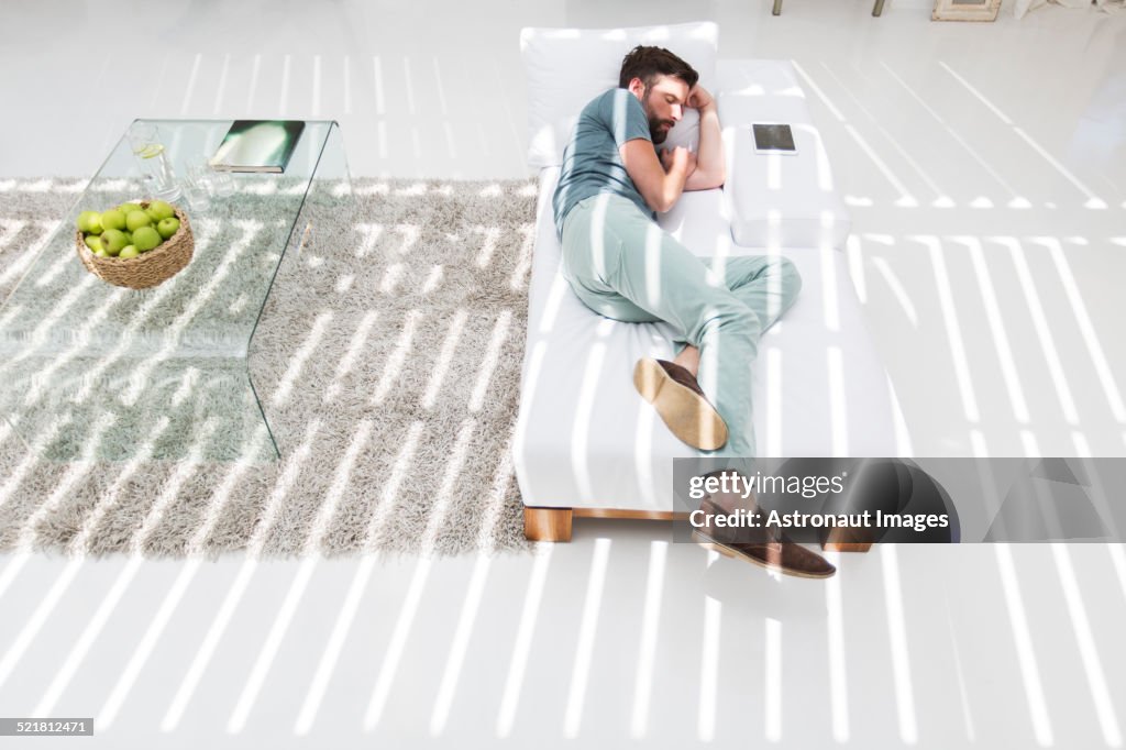 Hombre durmiendo la siesta en el sofá cama en la sala de estar moderna