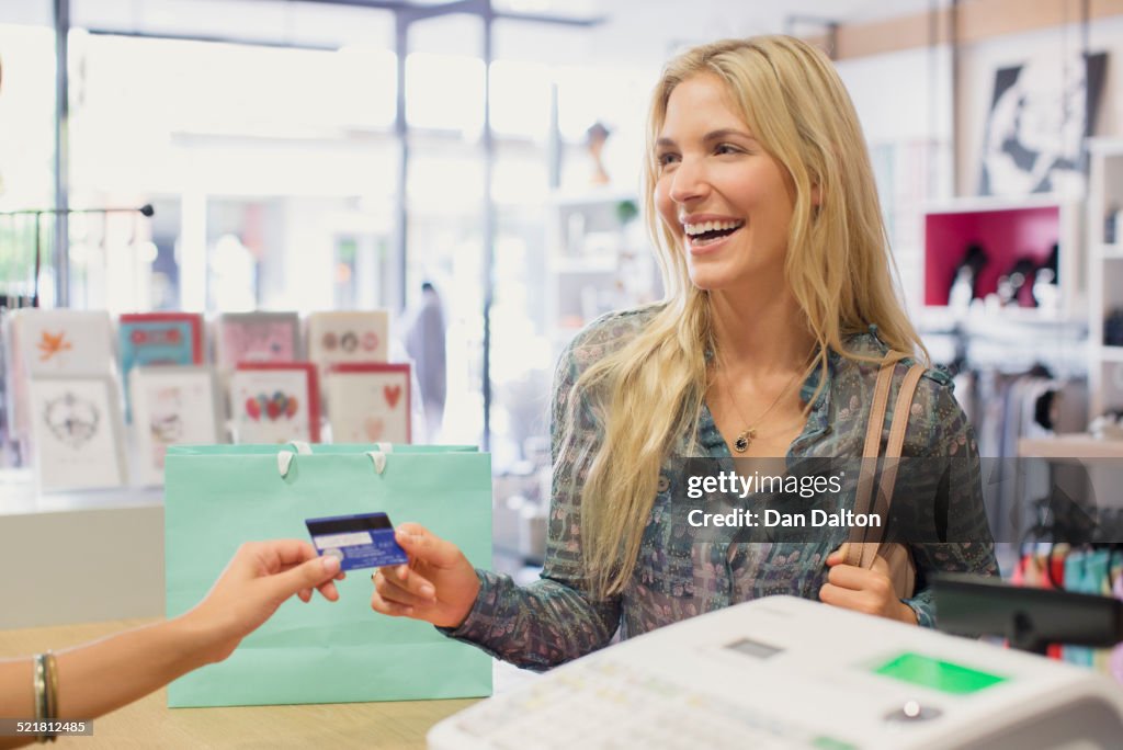 Mujer pagando con tarjeta de crédito en tienda de ropa