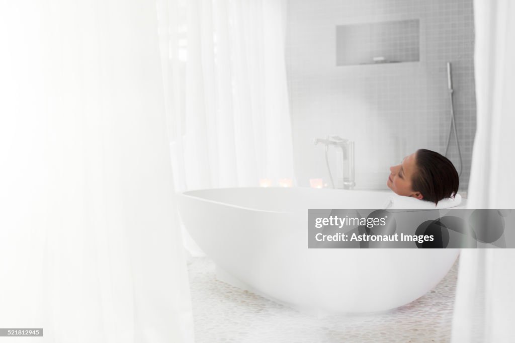 Woman relaxing in bath in modern bathroom