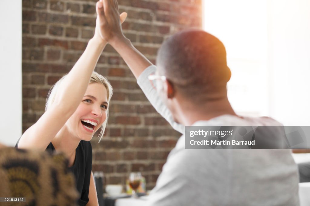 Business people high fiving at meeting in cafe