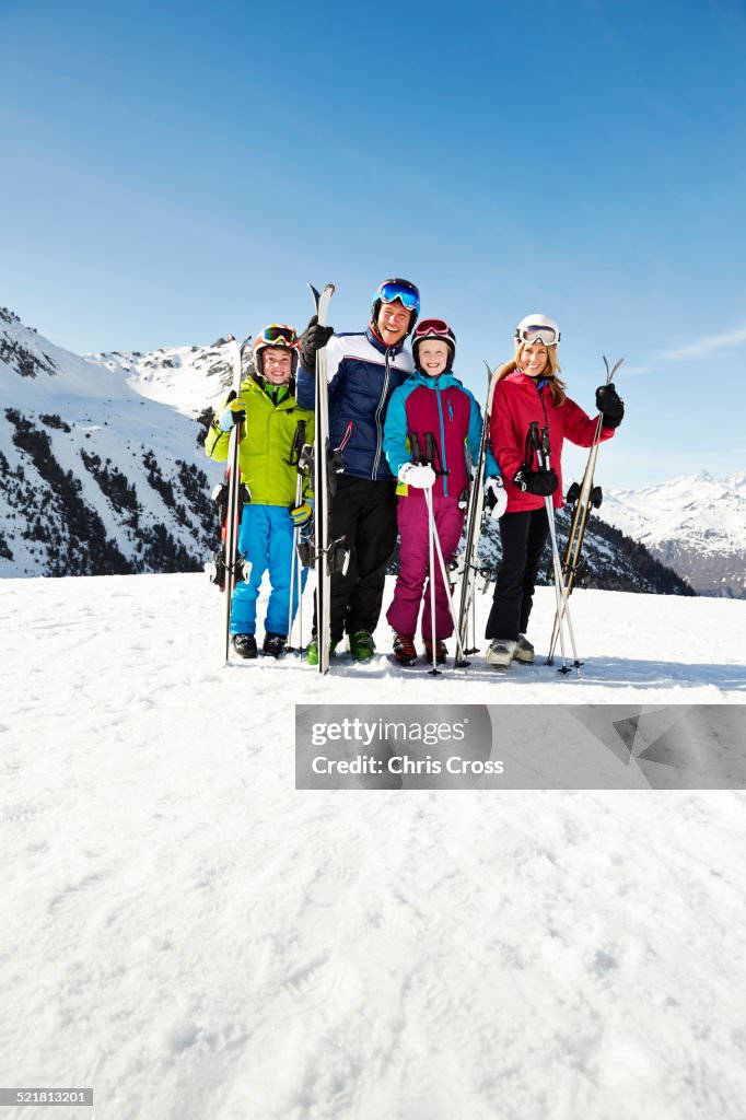Family holding skis on mountain top together