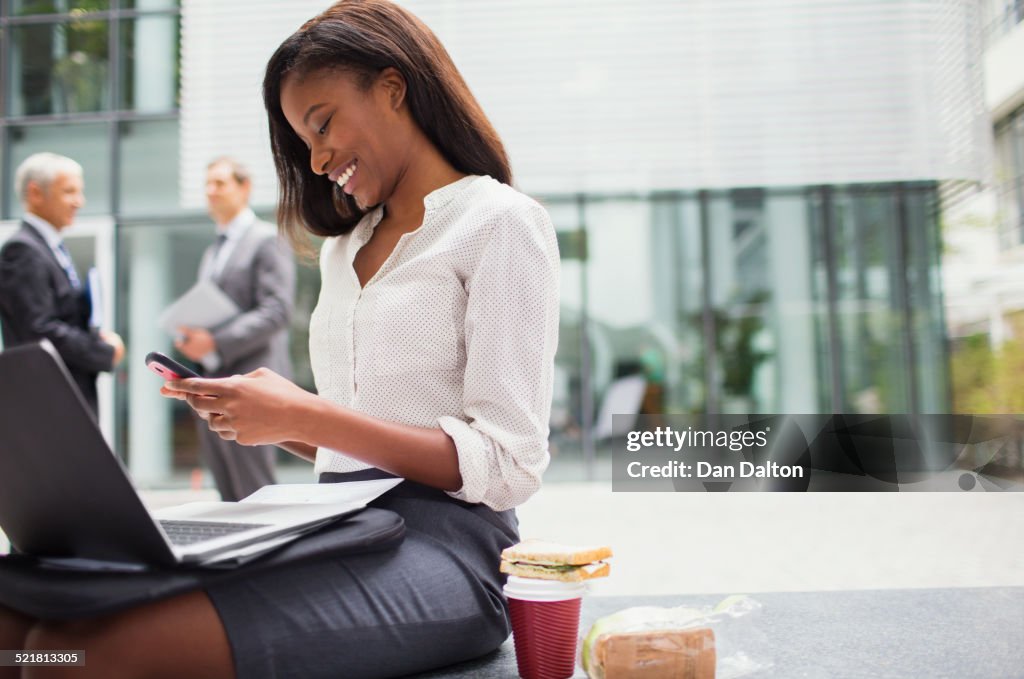 Mujer de negocios sentada en el banco usando el teléfono celular