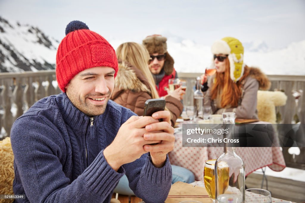 Hombre usando teléfono celular en balcón nevado