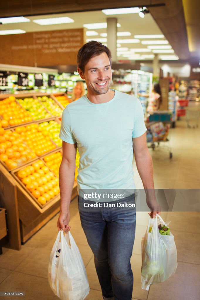 Man carrying shopping bags in grocery store