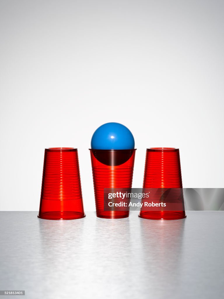 Blue ball in middle of three red cups