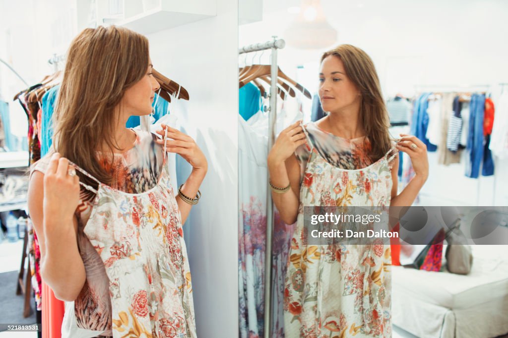 Mulher admirando vestido no espelho da loja